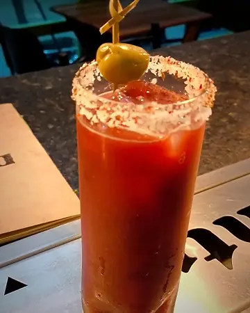 Bloody Mary em copo alto com borda de sal e azeitona