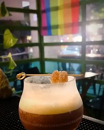 Coquetel escuro com colarinho de espuma e gengibre cristalizado