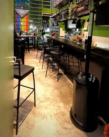Salão do Dentro: balcão, banquetas e bandeira do orgulho ao fundo